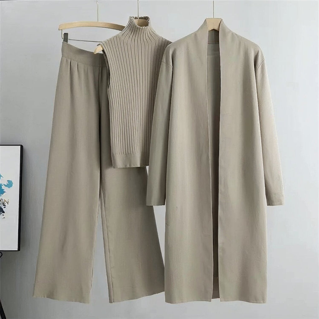 Beige outfit with pants, sweater, and coat on hangers against a light gray background