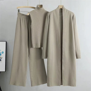 Beige outfit with pants, sweater, and coat on hangers against a light gray background