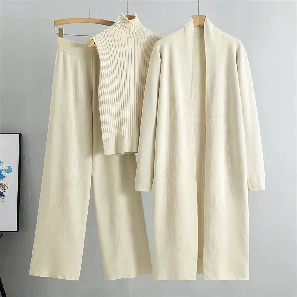 Beige outfit with a sweater, pants, and cardigan on hangers against a gray background.