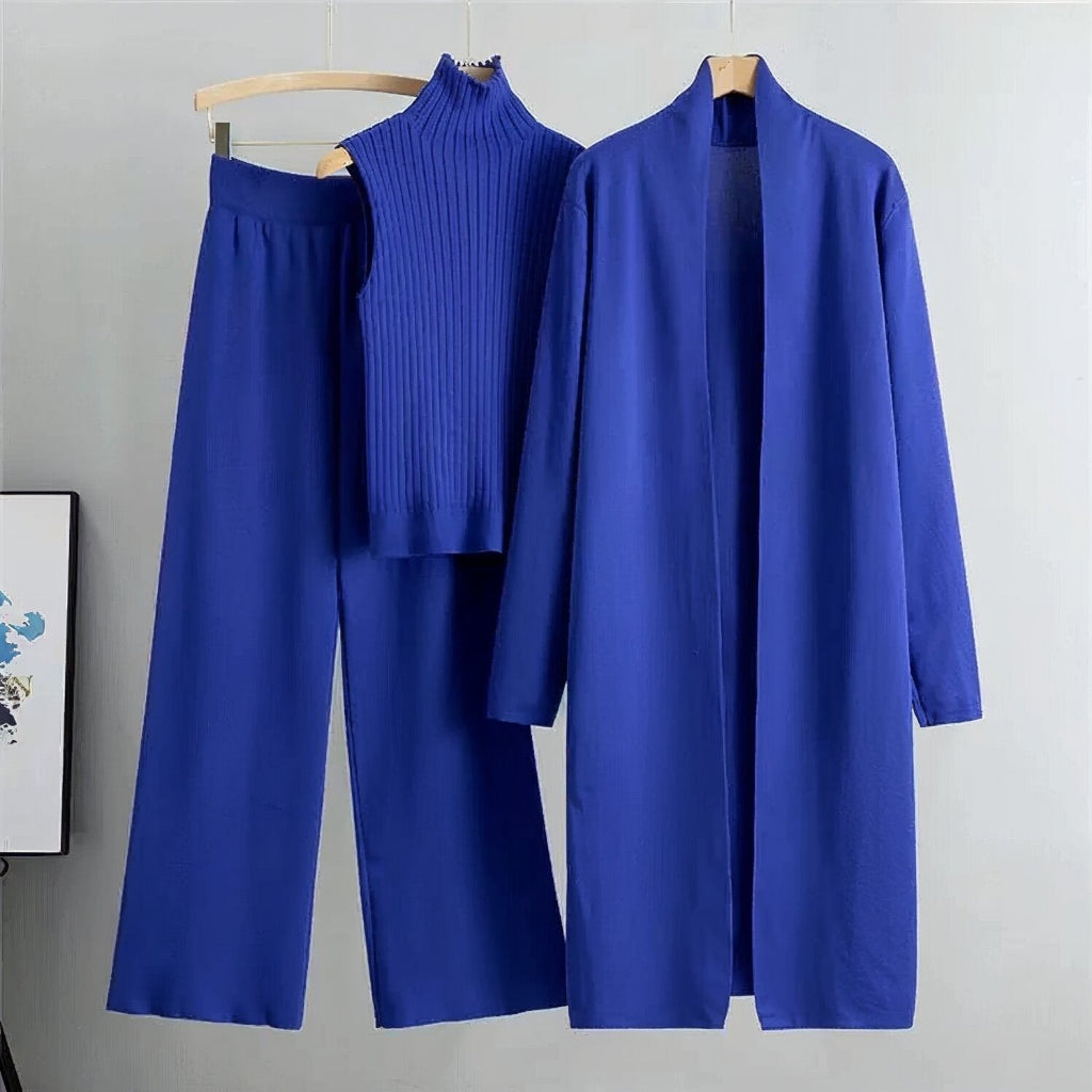 Blue outfit with a coat, pants, and turtleneck on hangers against a gray background