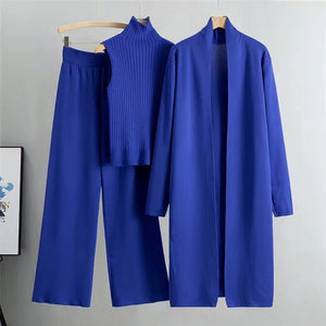 Blue outfit with a coat, pants, and turtleneck on hangers against a gray background