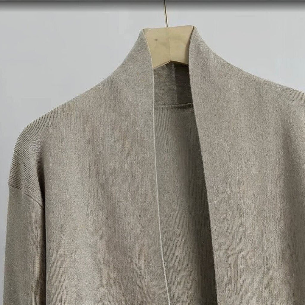Beige cardigan on a hanger against a white background