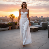 Woman in a white dress standing on a rooftop with a cityscape and sunset in the background