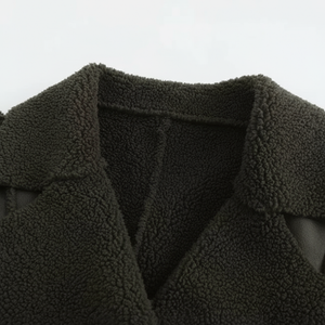 Close-up of a dark green fleece jacket with a collar on a light gray background