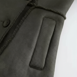 Close-up of a dark gray coat with a button and pocket on a white background