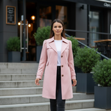 Woman wearing a pink trench coat walking down city steps.
