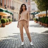 Woman in beige outfit standing on a cobbled street with blurred background