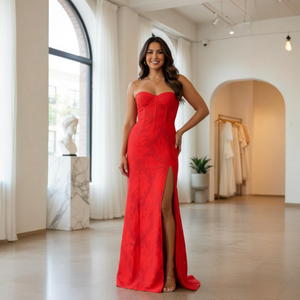 Woman in a red dress standing in a well-lit room with large windows.