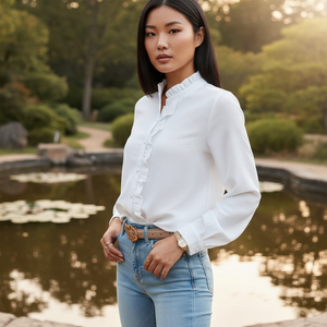 Woman wearing a white blouse and blue jeans standing by a pond with greenery in the background