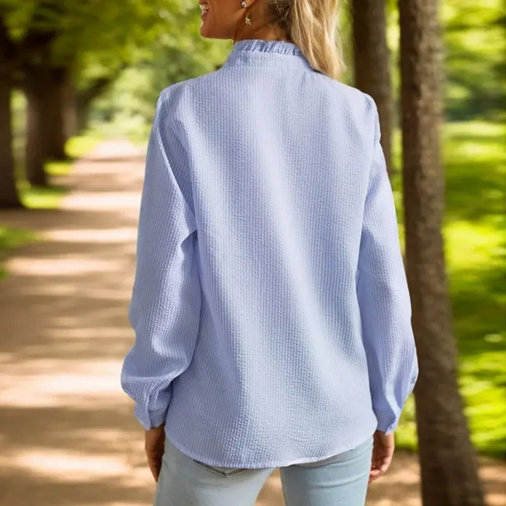 Woman wearing a light blue shirt walking on a path in a park
