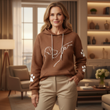 Woman wearing a brown hoodie with a dog design in a living room.