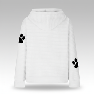 White hoodie with black paw prints on sleeves against a gray background