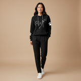 Woman wearing a black hoodie and pants with paw print design on a beige background