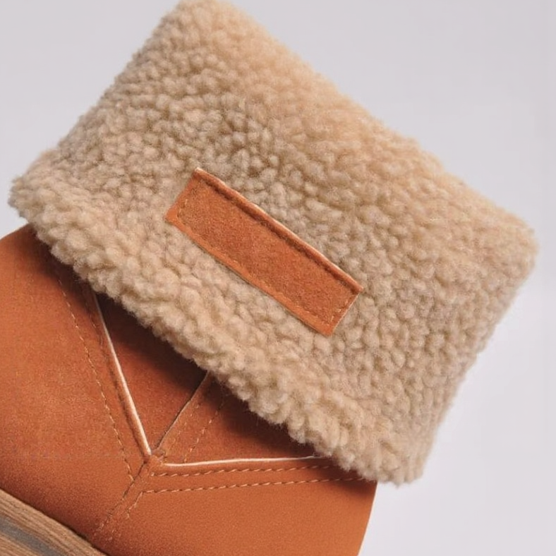 Close-up of a brown boot with beige shearling lining on a light gray background