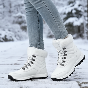 White winter boots with fur lining worn by a person on a snowy ground.