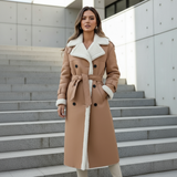 Woman wearing a tan coat with white fur trim standing on steps.