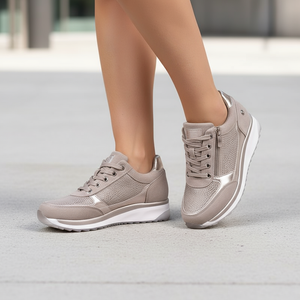 Beige sneakers worn by a person on a light gray surface