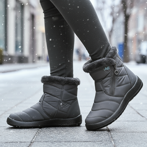 Gray winter boots with fur trim worn on a snowy street.