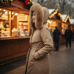 Person wearing a brown coat with a fur hood in a festive outdoor setting
