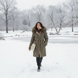 Woman in a long coat with fur hood walking in a snowy park