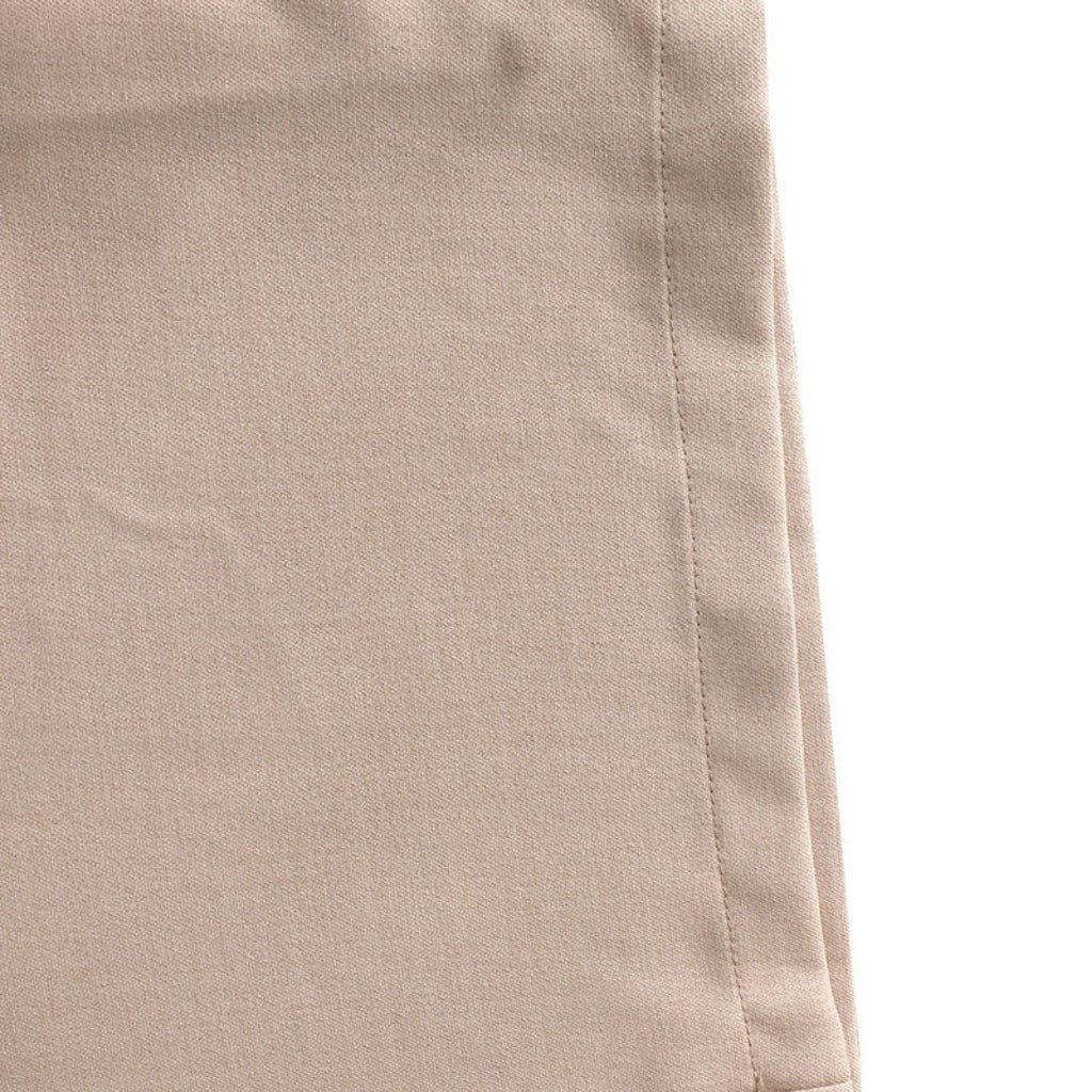 Close-up of beige pants with a visible seam on a white background