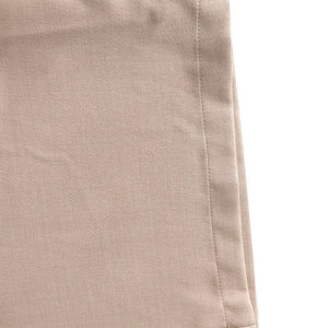 Close-up of beige pants with a visible seam on a white background