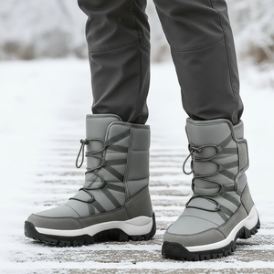 Gray winter boots with black soles worn by a person on a snowy ground.