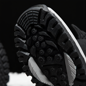 Close-up of a black and white shoe sole with tread pattern on a black background