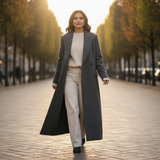 Woman in a long coat walking on a tree-lined street.