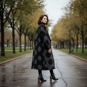 Woman in a black polka dot coat walking on a tree-lined street.