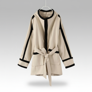 Beige coat with black trim on a hanger against a gray background