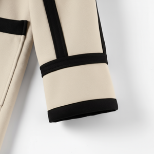 Close-up of beige pants with black trim on a light gray background