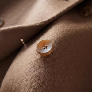 Close-up of a brown coat with a button on a white background