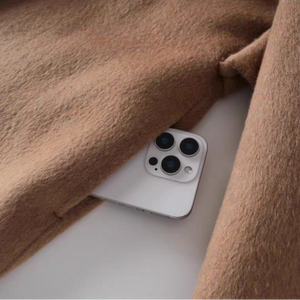 White smartphone with black camera module peeking out from a brown coat pocket