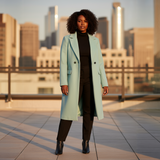 Woman in a light blue coat standing on a rooftop with city skyline in the background