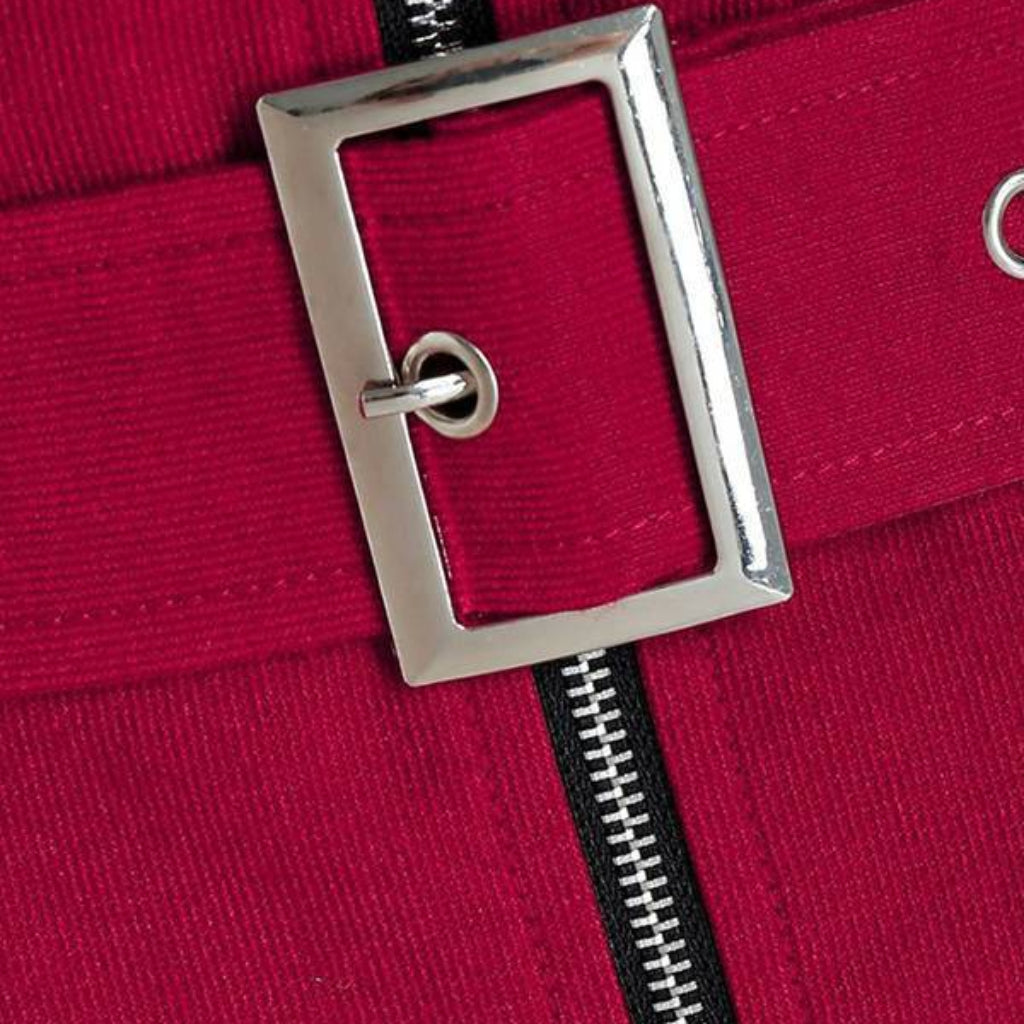 Close-up of a red garment with a silver buckle and black zipper.